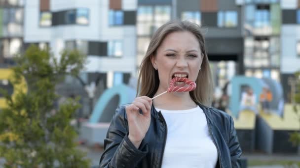 stylish caucasian young woman licking big lollipop on street - Filmmaterial, Video