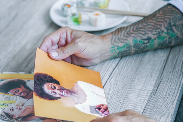 Adam eski kız arkadaşının fotoğraflarına bakıyor. Eller resme dokunuyor, suşi yemeğinin yanında. Resim - Fotoğraf, Görsel