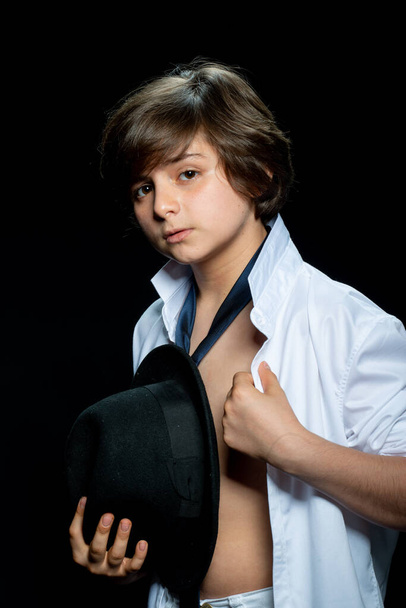 preteen boy in white shirt and hat posing on black background - Foto, afbeelding