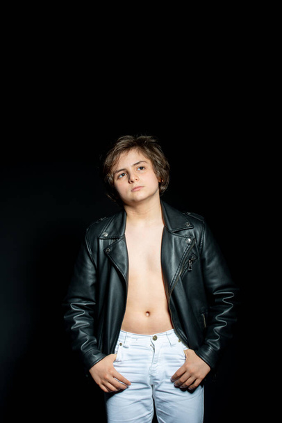 preteen boy in black leather jacket posing on black background - Foto, afbeelding