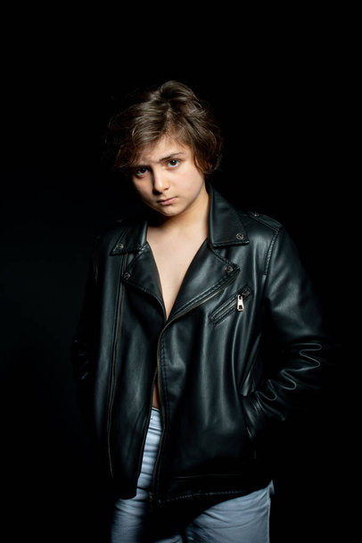 preteen boy in black leather jacket posing on black background - Фото, зображення