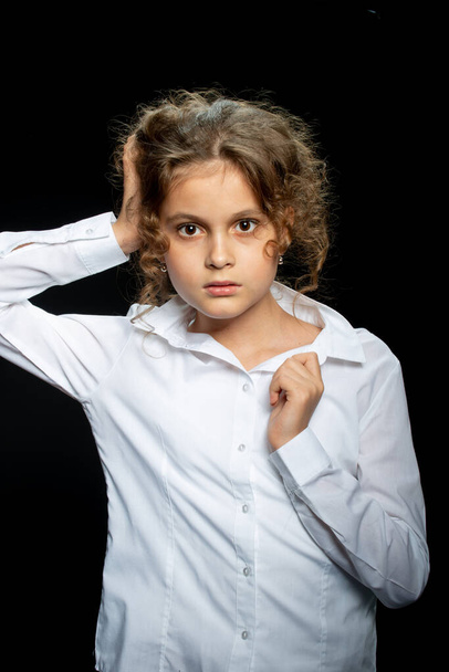 adorable preteen girl in white shirt posing on black background - Photo, Image