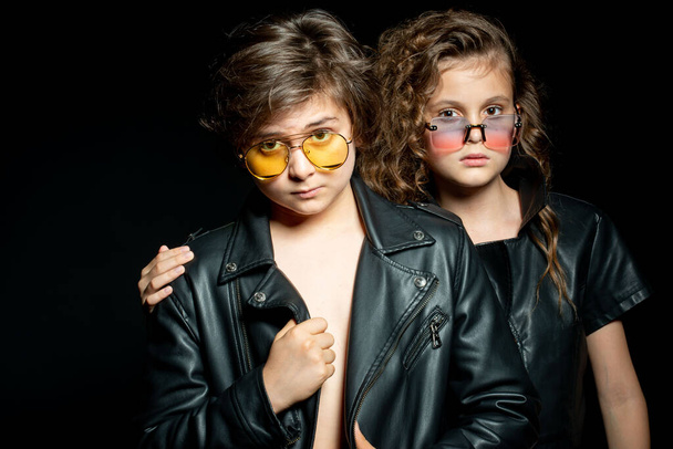 preteen boy and girl in leather clothes posing in studio on dark background - Foto, immagini