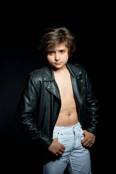 preteen boy in black leather jacket posing on black background - Valokuva, kuva