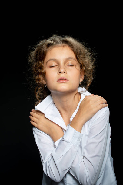 adorable preteen girl with closed eyes posing on black background - Foto, imagen