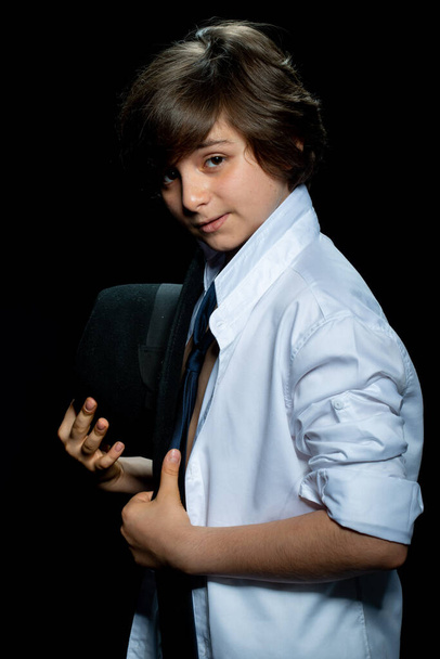 preteen boy in white shirt and hat posing on black background - Foto, imagen