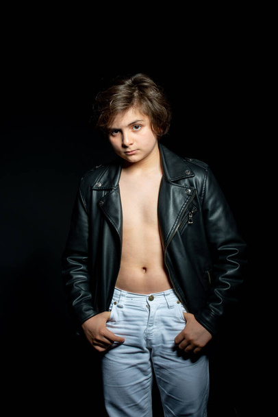 preteen boy in black leather jacket posing on black background - Valokuva, kuva