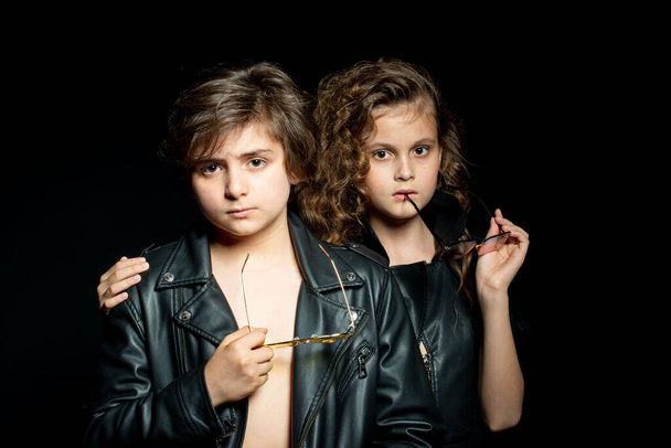preteen boy and girl in leather clothes posing in studio on dark background - Фото, зображення