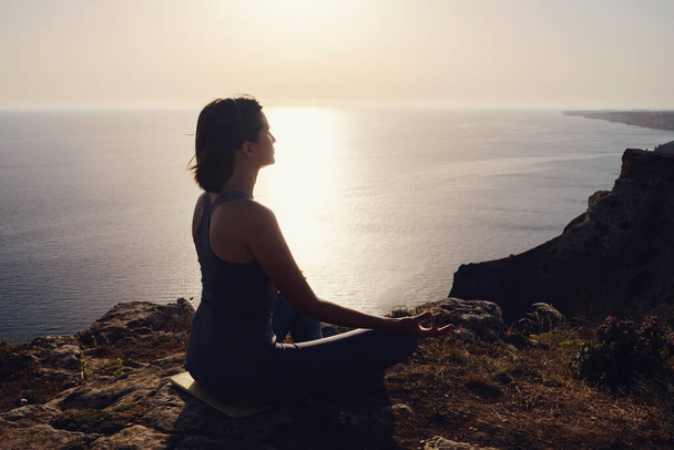 Nuori nainen joogaa auringonlaskun yli. meditaatio lootuksen asennossa. Joogasiluetti. Harmonian ja meditaation käsite. Terveellinen elämäntapa - Valokuva, kuva