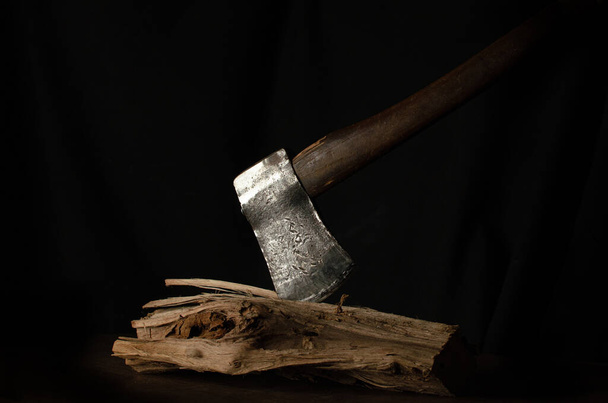 Μεταλλικό αιχμηρό τσεκούρι κολλημένο στο ξύλο με μαύρο φόντο - Φωτογραφία, εικόνα
