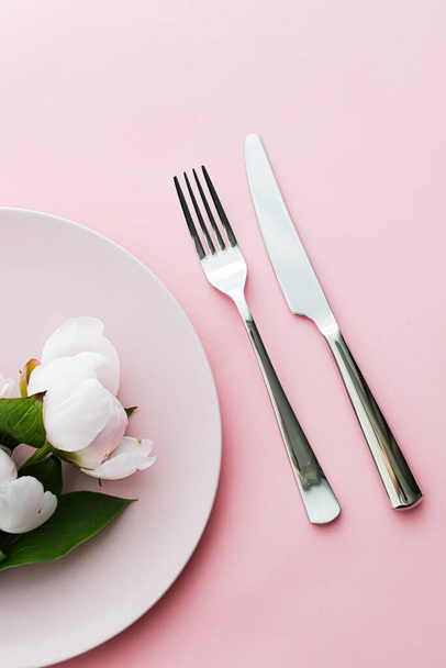 Talerz jadalny i sztućce z kwiatami piwonii jako dekoracja ślubna zestaw na różowym tle, top zastawy stołowe do dekoracji imprezy i menu marki - Zdjęcie, obraz
