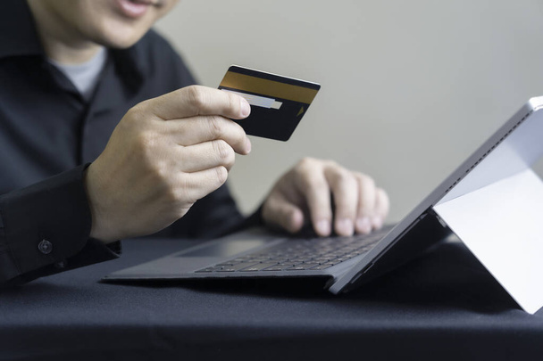 Mann bezahlt online per Kreditkarte mit digitalem Tablet oder Computer-Laptop, Internet-Banking oder E-Commerce-Konzept - Foto, Bild