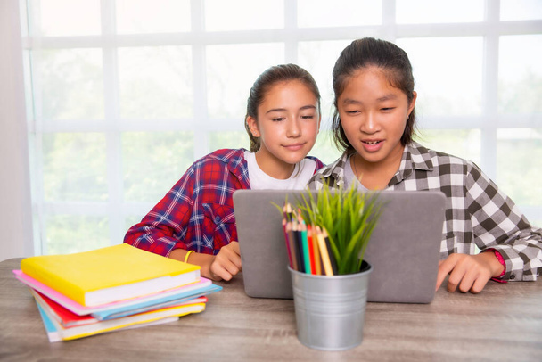 Due adolescenti ragazze studenti che guardano computer portatile, Home studio online o di lavoro dal concetto di casa
 - Foto, immagini