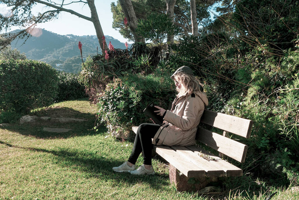 nő olvas egy könyvet ül egy bank körül a természet - Fotó, kép