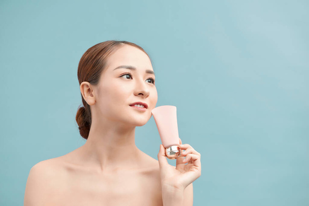 Beauty Youth Skin Care Concept - Belle femme caucasienne visage Portrait tenant et présentant produit tube crème
 - Photo, image