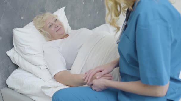 Friendly nurse holding elderly patient by hand, healthcare services, recovery - Video