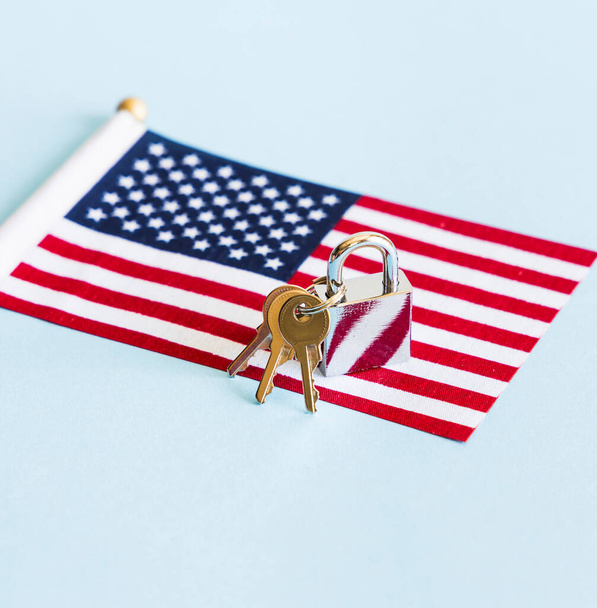 Metal silver padlock and keys with flag of the United States of America on blue background.  - Photo, image