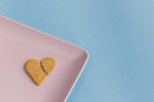 Kırık kalp. Kalp şeklinde kurabiye pembe bir tepside izole edilmiş. Açık mavi arkaplan. Boşluğu kopyala - Fotoğraf, Görsel