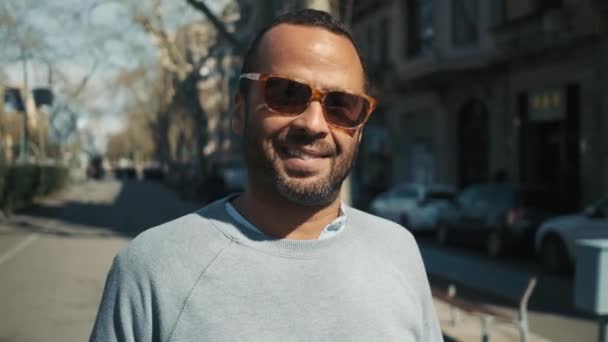 Muotokuva luottavainen hymyilevä liikemies aurinkolasit onnellisesti poseeraa kameran ulkona - Materiaali, video