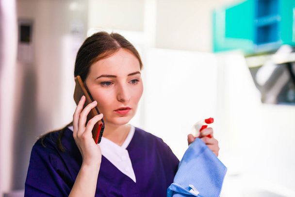 woman in cleaning service uniform using mobile phone - Photo, Image