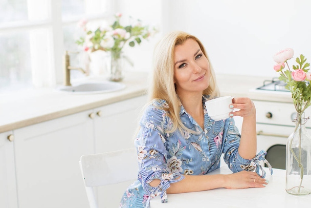 Pretty mature woman enjoying morning coffee at home. - Foto, afbeelding