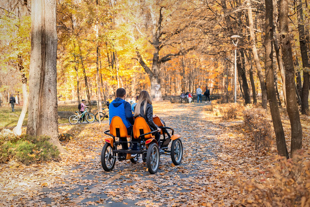 Pareja de personas disfrutan de montar pedal surrey carrito de alquiler de bicicletas o compartir al aire libre en el hermoso parque dorado de otoño de la ciudad, jardín o bosque en un día cálido y brillante. Familia sana fuera de la actividad recreativa deportiva
 - Foto, Imagen