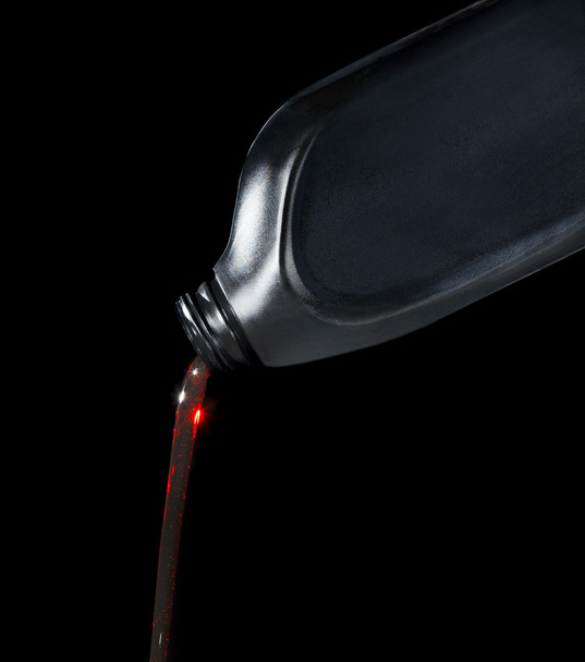 lubricante de aceite de motor rojo que vierte de botella de plástico negro
 - Foto, Imagen