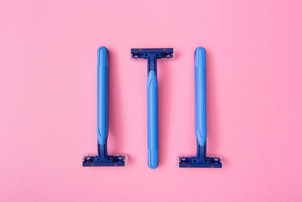 3 hojas de afeitar desechables azules sobre fondo de cartón rosa
 - Foto, imagen
