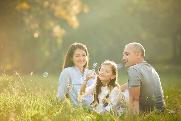 família feliz com criança menina bolhas de sabão golpe
 - Foto, Imagem