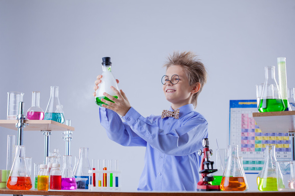 Funny smiling boy holding flask with reagent - Foto, Imagem