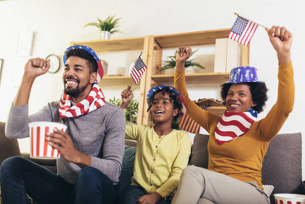 3 つのテレビを見て、自宅のソファの上のスポーツ ゲームを応援の幸せなアフリカ系アメリカ人家族 - 写真・画像
