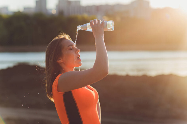 Slim young woman drinking water after training. - Foto, immagini