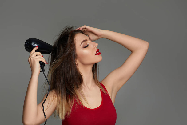young woman drying her hair with dryer - Фото, зображення