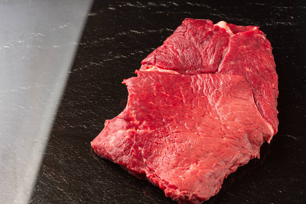 Fresh raw  beef meat. Piece of fresh red meat with black stone background. - Foto, Imagen