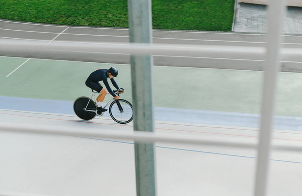 Profi kerékpáros a sporteszközök vonatok egy üres velodrome. Bicikliztem a Velodrome-on. Háttér. Szakmai kerékpározás. - Fotó, kép