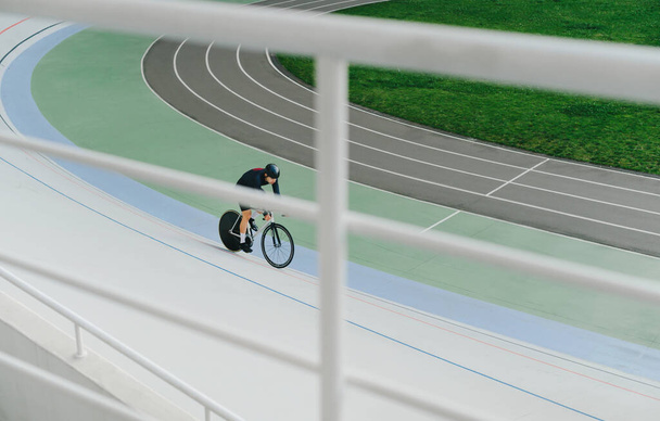 Fietser en track bike treinen op een lege velodrome. Fietsen als hobby. Fietstraining van het velodroom. Bovenaanzicht, achtergrond - Foto, afbeelding