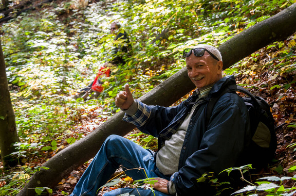 Holiday and leisure concept. Portrait of an elderly man resting and sitting in the forest - Foto, imagen