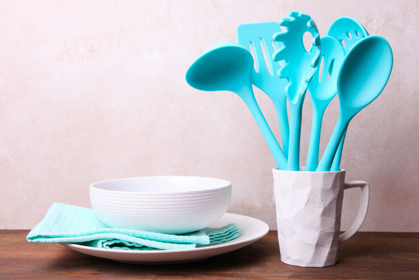 Conjunto de utensilios de cocina azules en una taza de cerámica y platos sobre un fondo neutro
. - Foto, Imagen
