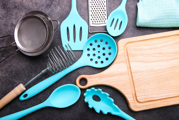Set of different kitchen utensils and cutting board on a black background. - Photo, Image