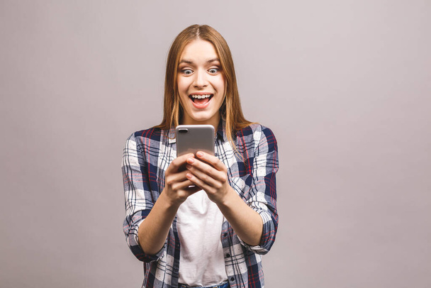 Foto van vrolijke schattige mooie jonge vrouw chatten door mobiele telefoon geïsoleerd over grijze muur achtergrond. - Foto, afbeelding