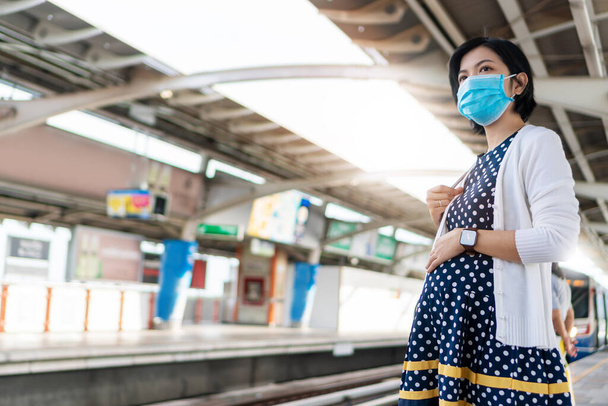 Asiatico gravidanza donna indossare faccia maschera attesa cielo treno mentre andare in ufficio. Giovane madre nei trasporti pubblici durante il virus pandemico. Assistenza sanitaria in Nuova distanza normale e sociale. - Foto, immagini