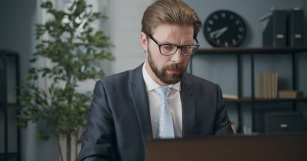 Mature businessman in eyeglasses using laptop for work - Imágenes, Vídeo