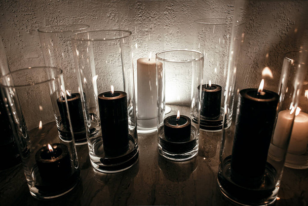 bougies élégantes noir et blanc dans des flacons en verre près de la cheminée. - Photo, image