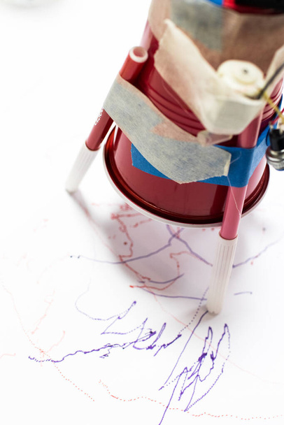 Пластиковая чашка с двигателем постоянного тока и батарейками, написанная маркером на белом листе бумаги. Образовательная деятельность STEAM для детей в школе. Автономный робот, который пишет дети с отходами
 - Фото, изображение