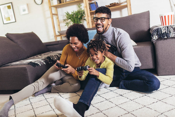 African American family at home sitting in sofa couch and playing console video games together - Foto, Imagen