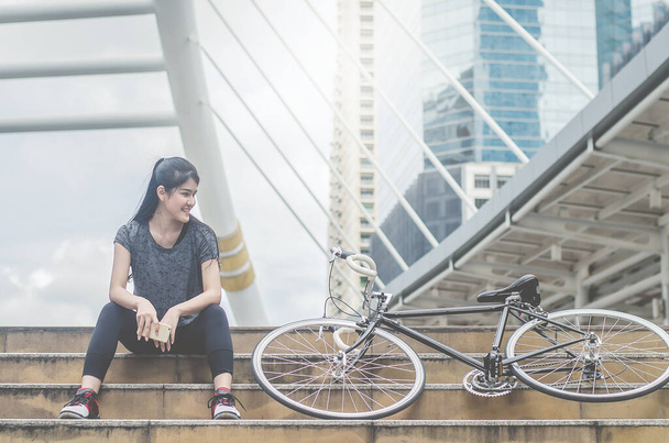 Sport kobieta siedzi na schodach jest delegowania z jej rower w mieście - Zdjęcie, obraz