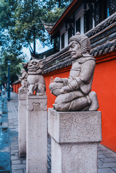 Rode Muur Stenen aap, Stenen leeuw Stenen soldaat sculptuur, Wenshu klooster, Chengdu, Sichuan, China.Stenen leeuw sculptuur met rode muur als achtergrond in Wenshu klooster, Chengdu, Sichuan, China. - Foto, afbeelding