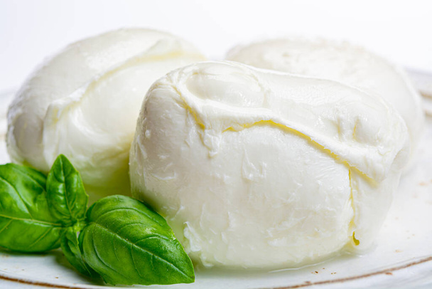 Queso blando italiano mozzarella, queso blanco hecho de leche de vaca o búfalo con hierba de albahaca verde fresca de cerca
 - Foto, Imagen