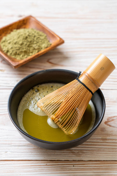 hot matcha green tea cup with green tea powder and bamboo whisk - Фото, изображение