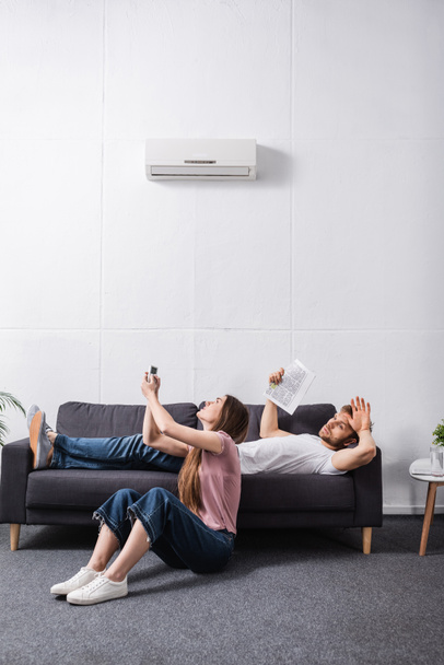 θυμωμένο ζευγάρι που υποφέρει από θερμότητα, ενώ κάθεται στο σπίτι με σπασμένο κλιματιστικό  - Φωτογραφία, εικόνα
